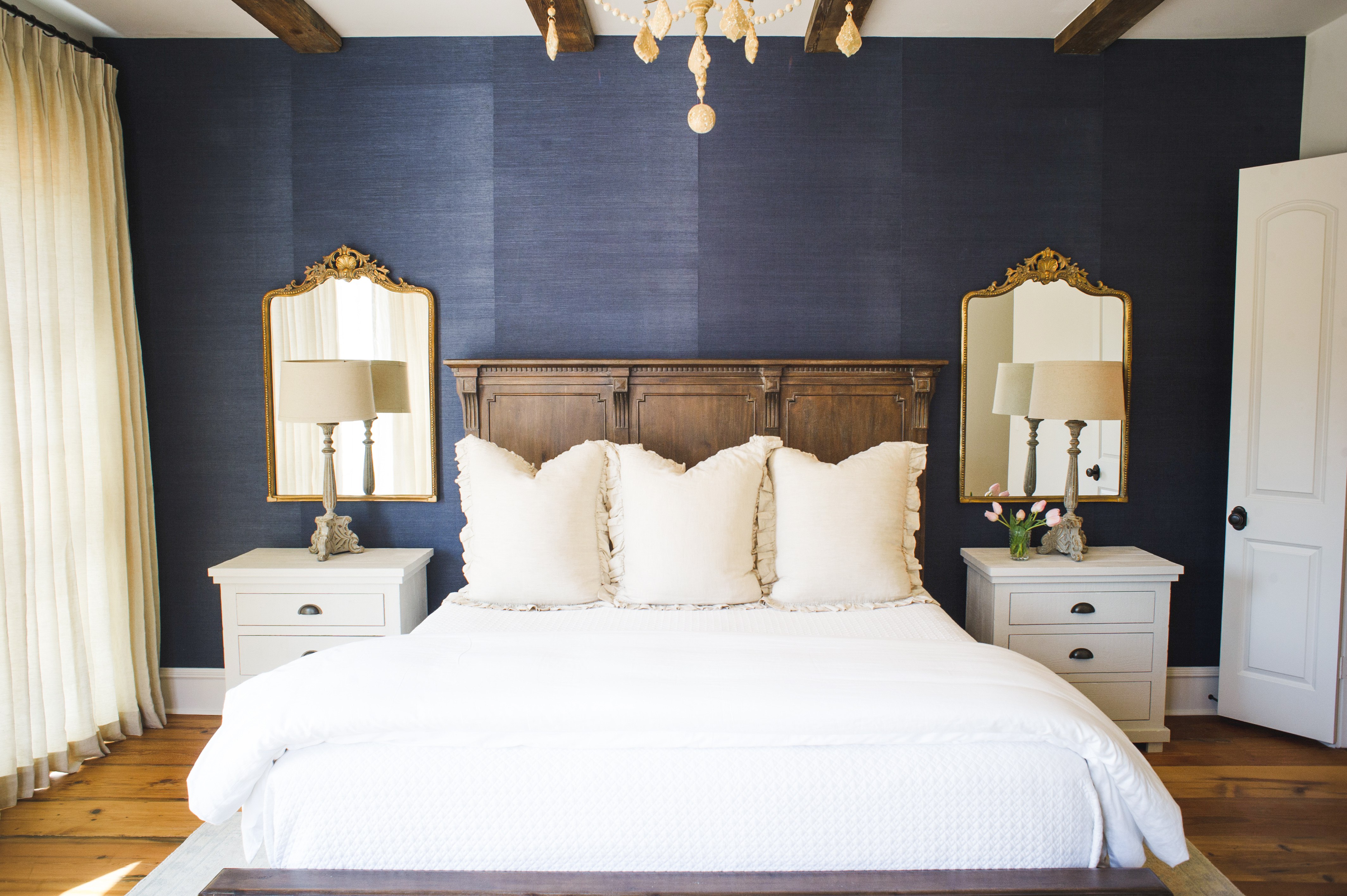 Navy bedroom with gold mirrors and wood headboard
